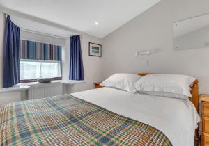 a bedroom with a bed and a window with blue curtains at Camelot, Newport - A Pembrokeshire Waterside Cottage in Newport Pembrokeshire