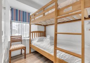 a bedroom with two bunk beds and a chair at Camelot, Newport - A Pembrokeshire Waterside Cottage in Newport Pembrokeshire