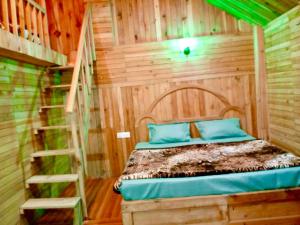 a bed in a wooden room with a ladder at woodland duplex cottage 2 Jibhi in Jibhi