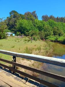 a bridge over a river next to a field at Cabaña de Campo in San José de la Mariquina +5 photos