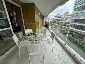 a balcony with a glass table and chairs on it at Ap Completo /Ar e Wi-Fi/ Riviera in Riviera de São Lourenço