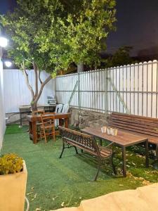 Dos bancos y una mesa en un patio con valla en דירת חדר נעימה במיקום פסטורלי, en Kiryat Shemona