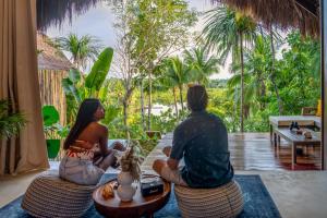 two people sitting on chairs in a room looking out at the jungle at Private Villa with Pool - Kalani River Villas in General Luna