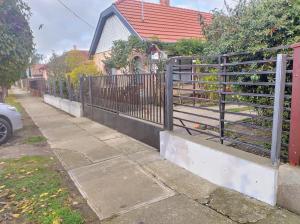 a fence on a sidewalk next to a house at Bundik Vendégház in Berettyóújfalu
