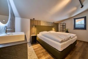 a bedroom with a large bed and a sink at MiLa Apartments in Saalbach Hinterglemm