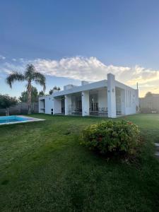 RivadaviaPuyuta beach的一座白色的建筑,有院子和棕榈树