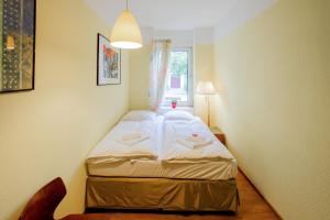 a small room with a bed with white sheets at Holiday Berlin Apartments in Berlin +25 photos