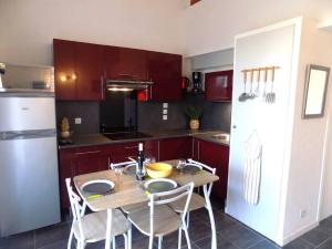 cocina con mesa de madera con sillas y nevera en Saint Palais sur Mer - ADORABLE VILLA en résidence avec PISCINE COLLECTIVE, en Saint-Palais-sur-Mer