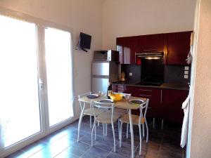 Una cocina con mesa y sillas y un refrigerador. en Saint Palais sur Mer - ADORABLE VILLA en résidence avec PISCINE COLLECTIVE, en Saint-Palais-sur-Mer