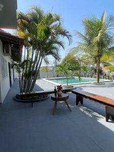 un patio con bancos, palmeras y una piscina en Villa Rocha mar, en São José de Ribamar