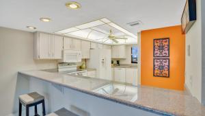 a large kitchen with white cabinets and an orange wall at Relaxing Ocean Condo Steps from the Beach in Daytona Beach Shores +19 photos