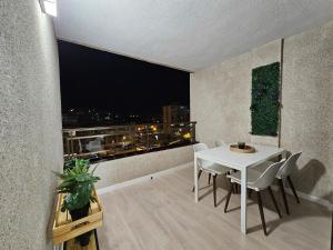 Un comedor con una mesa blanca y un gran ventanal. en Los Cristianos - Valdes Center 9 - As de Casas, en Los Cristianos