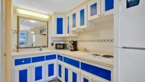une cuisine avec des armoires bleues et blanches et un réfrigérateur dans l'établissement Direct Ocean Views at Daytona Beach Resort, à Daytona Beach