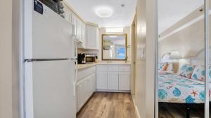 Un dormitorio con una cama y una cocina con nevera. en Daytona Beach Getaway with Direct Ocean Views, en Daytona Beach