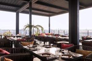 ein Esszimmer mit Tischen und Stühlen und großen Fenstern in der Unterkunft Riviera Royal Hotel in Conakry