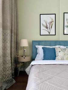 a bedroom with a blue bed and a table with a lamp at GreenLine Terra in Astana