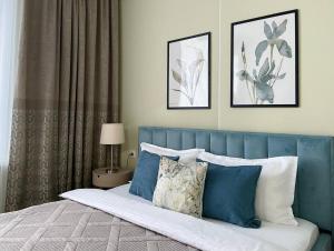 a bed with a blue headboard and pillows on it at GreenLine Terra in Astana