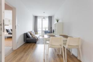 a white living room with a table and chairs at Urban Chic - Luxury 2-Bedroom Apartment in Warsaw City Center, Pereca Street in Warsaw +14 photos