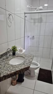 a white bathroom with a sink and a toilet at 103-FLAT-Espaço, conforto.É disso que você precisa in Anápolis +8 photos