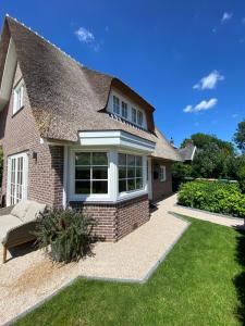 a detached house with a thatched roof at Luxe Garden Villa Blaricum AMS Area in Blaricum