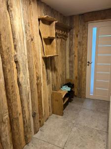 a room with a wooden wall with shelves and a door at Pūnas in Cēsis