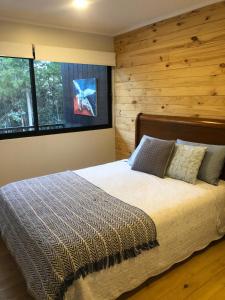 a bedroom with a large bed with a wooden wall at Hermosa casa en el bosque in Algarrobo