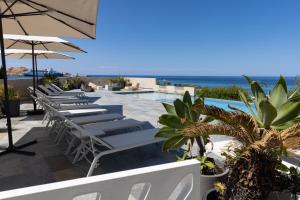 a row of chairs and umbrellas next to a pool at Residence Saletta Mare in LʼÎle-Rousse