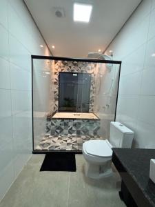 a bathroom with a toilet and a glass wall at Pousada Avenida Farol in Campos dos Goytacazes +39 photos