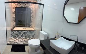 a bathroom with a toilet and a sink and a shower at Pousada Avenida Farol in Campos dos Goytacazes