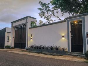 a white building with black doors on a street at Tiamo Rooms in Matara +10 photos