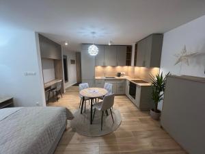 a bedroom with a bed and a table and a kitchen at Apartamenty Novela Centrum in Słupsk