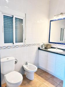 a white bathroom with a toilet and a sink at Can Pines in Paradas +14 photos