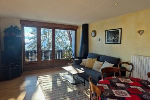 ein Wohnzimmer mit einem blauen Sofa und einem Tisch in der Unterkunft Appartement cosy au cœur de La Féclaz in La Feclaz