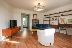 ein Wohnzimmer mit einem blauen Sofa und einem Fernseher in der Unterkunft La Villa Seventies - Parking gratuit in Angoulême