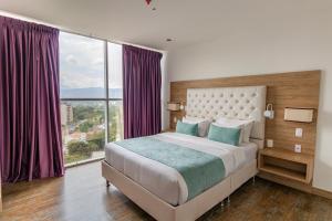 a bedroom with a bed and a large window at Hotel Roseliere Bucaramanga in Bucaramanga