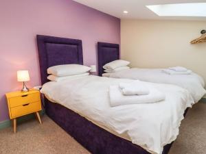 Dos camas en una habitación con paredes moradas. en Bears Court Barn 4, en Cheltenham