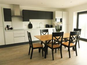 a kitchen and dining room with a wooden table and chairs at Glynllifon 2 in Llanallgo