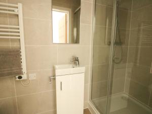 a bathroom with a shower and a sink and a mirror at Glynllifon 2 in Llanallgo