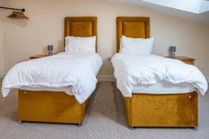 two beds in a room with white sheets and pillows at Bears Court Barn 7 in Cheltenham