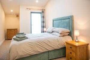 a bedroom with a large bed with a blue headboard at Bears Court Barn 5 in Cheltenham