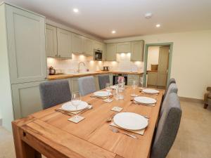 a wooden table with chairs and plates and wine glasses at Bears Court Barn 3 in Cheltenham