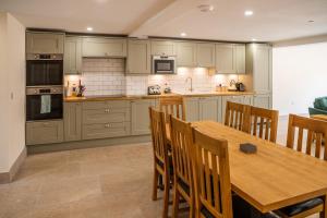 a kitchen with a wooden table and wooden chairs at Bears Court Barn 6 in Cheltenham