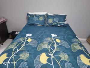 a bed with a green comforter and two pillows at 27 on Milton in Cape Town