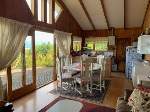 a dining room and kitchen with a table and chairs at Cabaña Licanray, vista volcán Villarrica y lago Calafquén in Licán Ray
