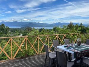 a table and chairs on a deck with a view at Cabaña Licanray, vista volcán Villarrica y lago Calafquén in Licán Ray