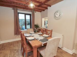 een eettafel met stoelen en een klok aan de muur bij Providence Cottage in Whitby