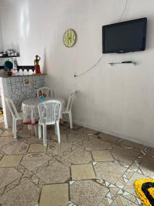Un comedor con mesa y sillas y un televisor. en Casa em vila familiar, en Natal