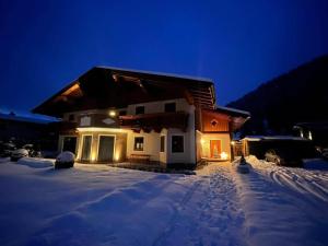 een huis in de sneeuw 's nachts met lichten bij Familie Meilinger - Werfenweng Ferienappartements in Werfenweng
