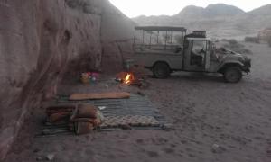 ワディ・ラムにあるWadi rum nightsの砂漠の火のそばに駐車されたジープ +14枚の写真