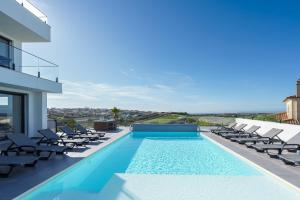 a swimming pool with chaise lounges and chairs on a house at Villa Gold with ocean view, jacuzzi and private pool in Ribamar